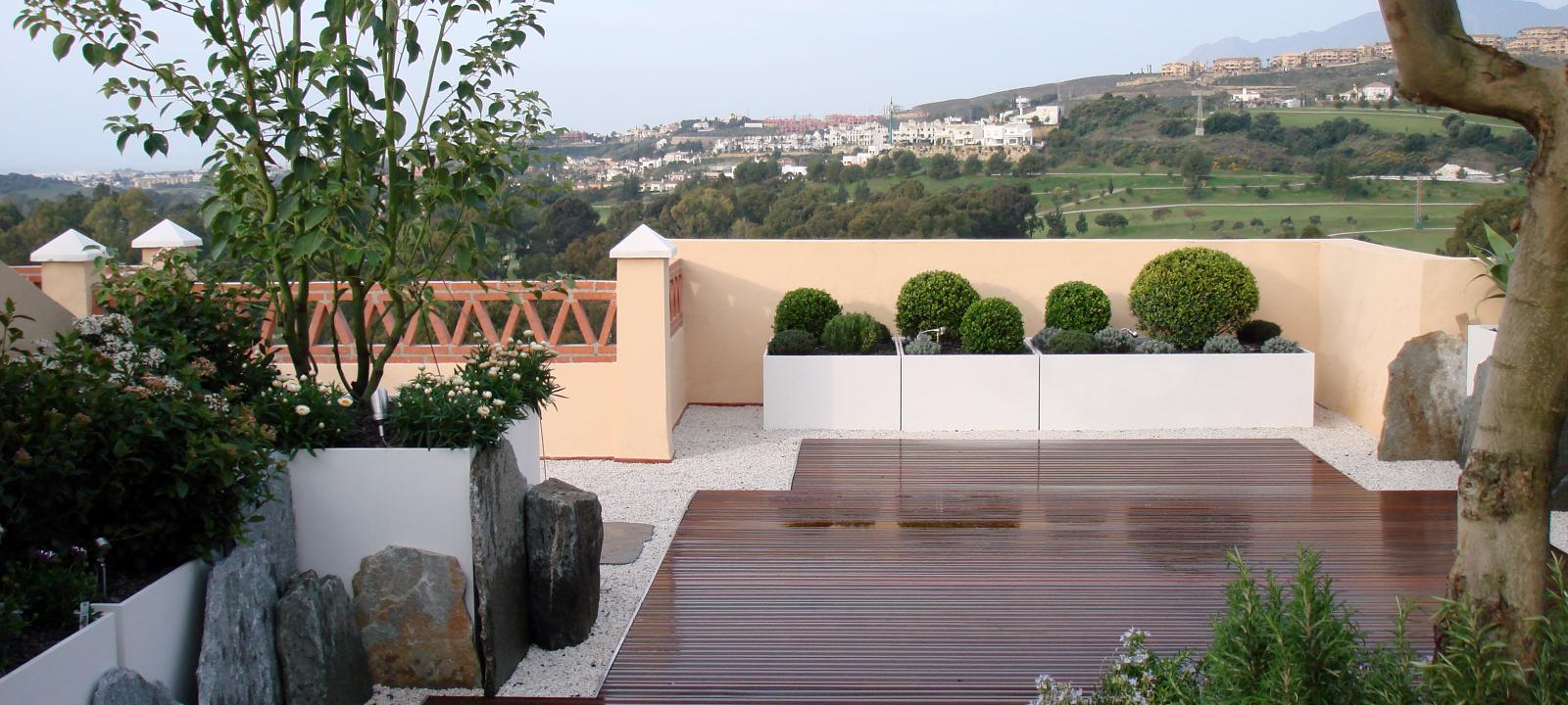 Terraza con pavimentos de madera y olivos, boj y romero en macetas