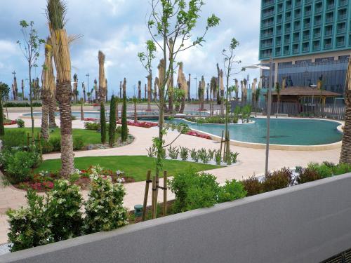 Un parque con palmeras, zonas peatonales y piscinas sobre una cubierta de garaje subterráneo