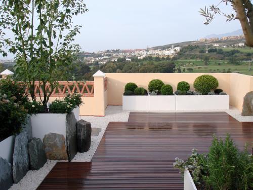 Terraza con pavimentos de madera y olivos, boj y romero en macetas